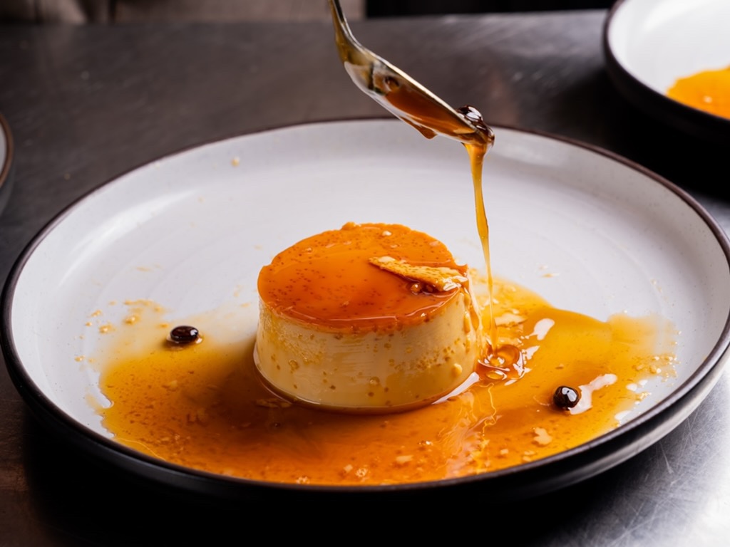 Caramel sauce being spooned over a Mexican flan
