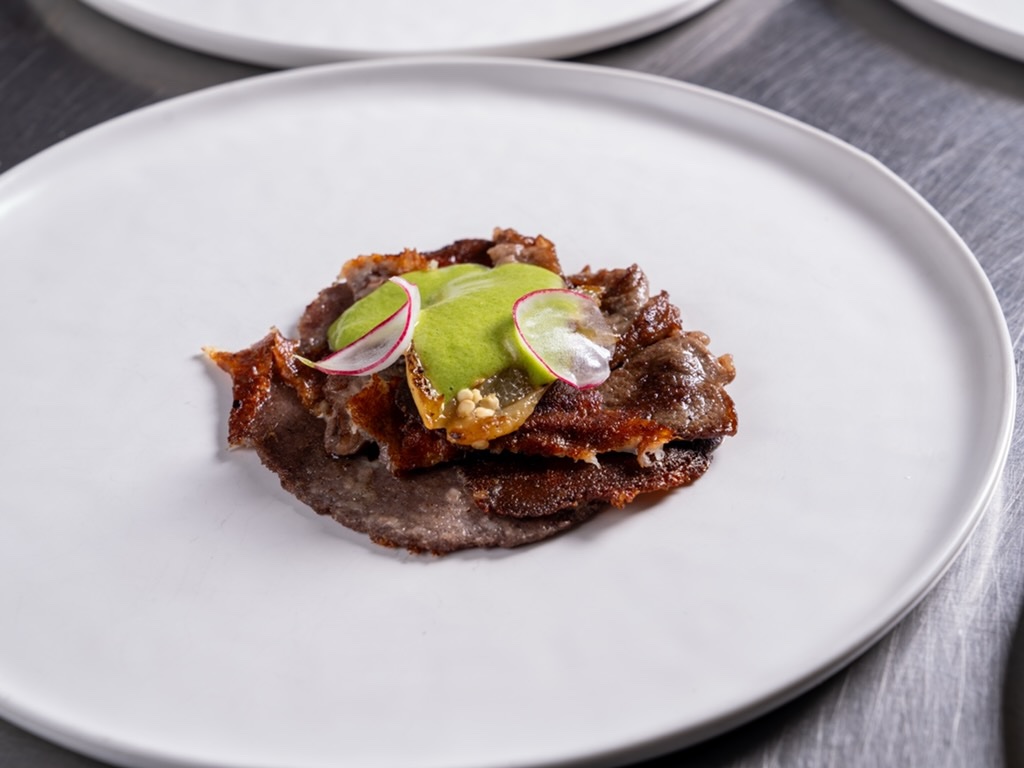 Blue corn tostada with crispy pork, avocado and shaved radish