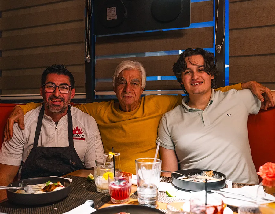 Chef with guests seated at a booth during a dinner event