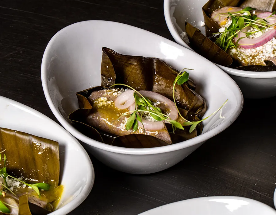 Fish cooked in banana leaf with pickled onion and microgreens