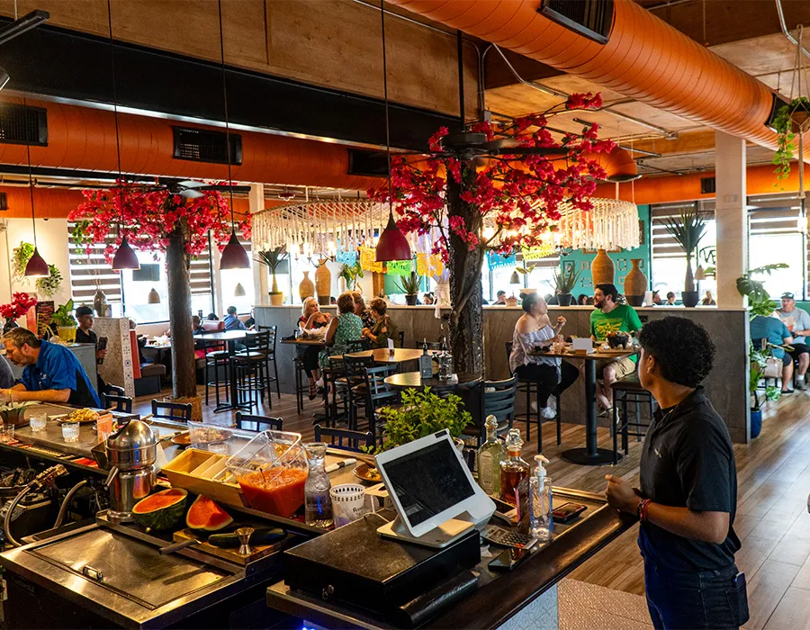 Rumbo 52 bar and dining room with red floral trees and pendant lights